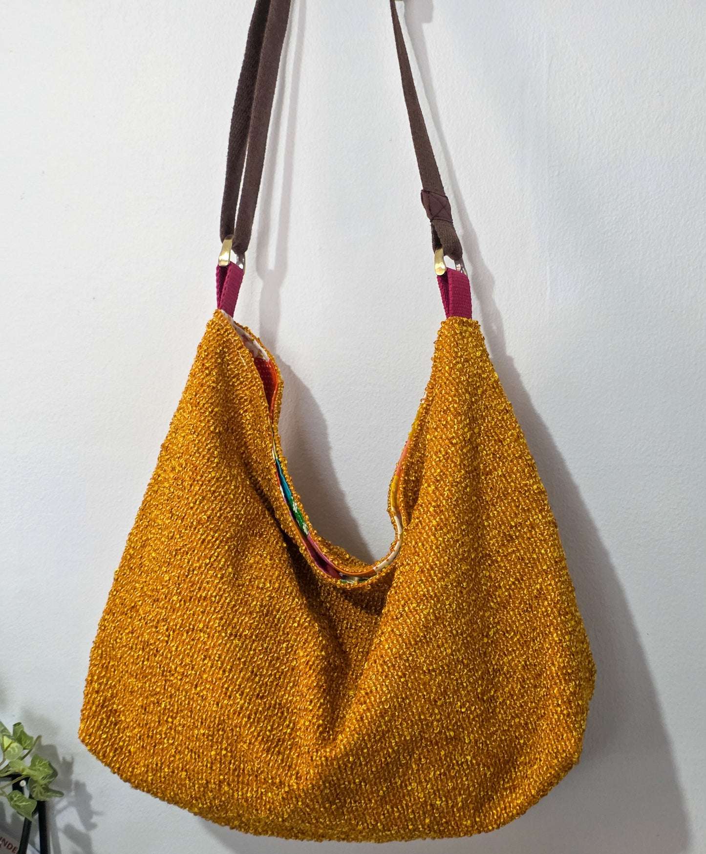 Yellow textured handbag with a brown strap on a white background