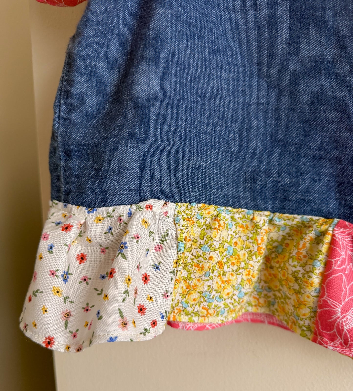 Close-up of a denim shirt with colorful floral and patterned fabric trim.