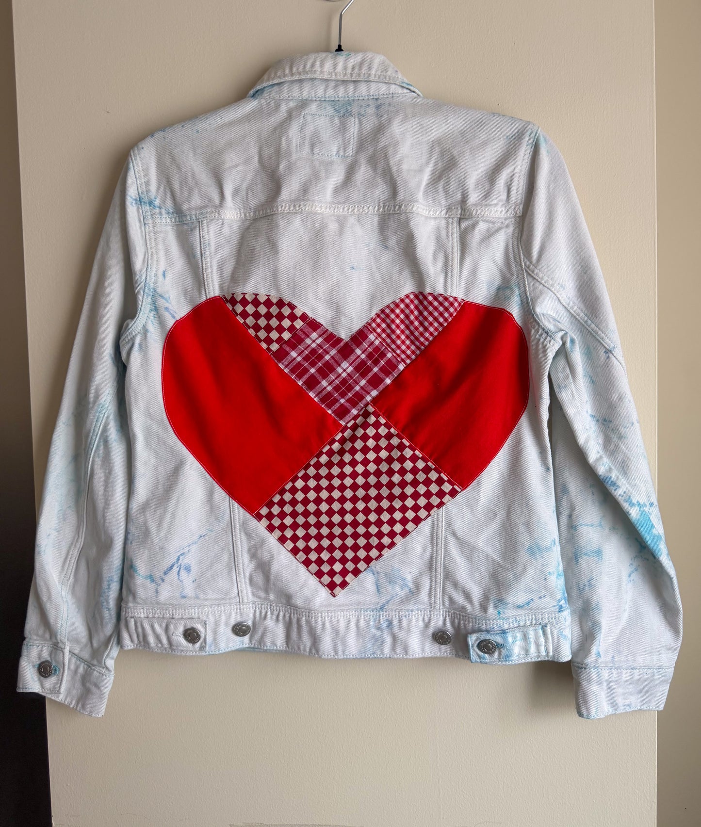 White denim jacket with a red heart design on a beige background