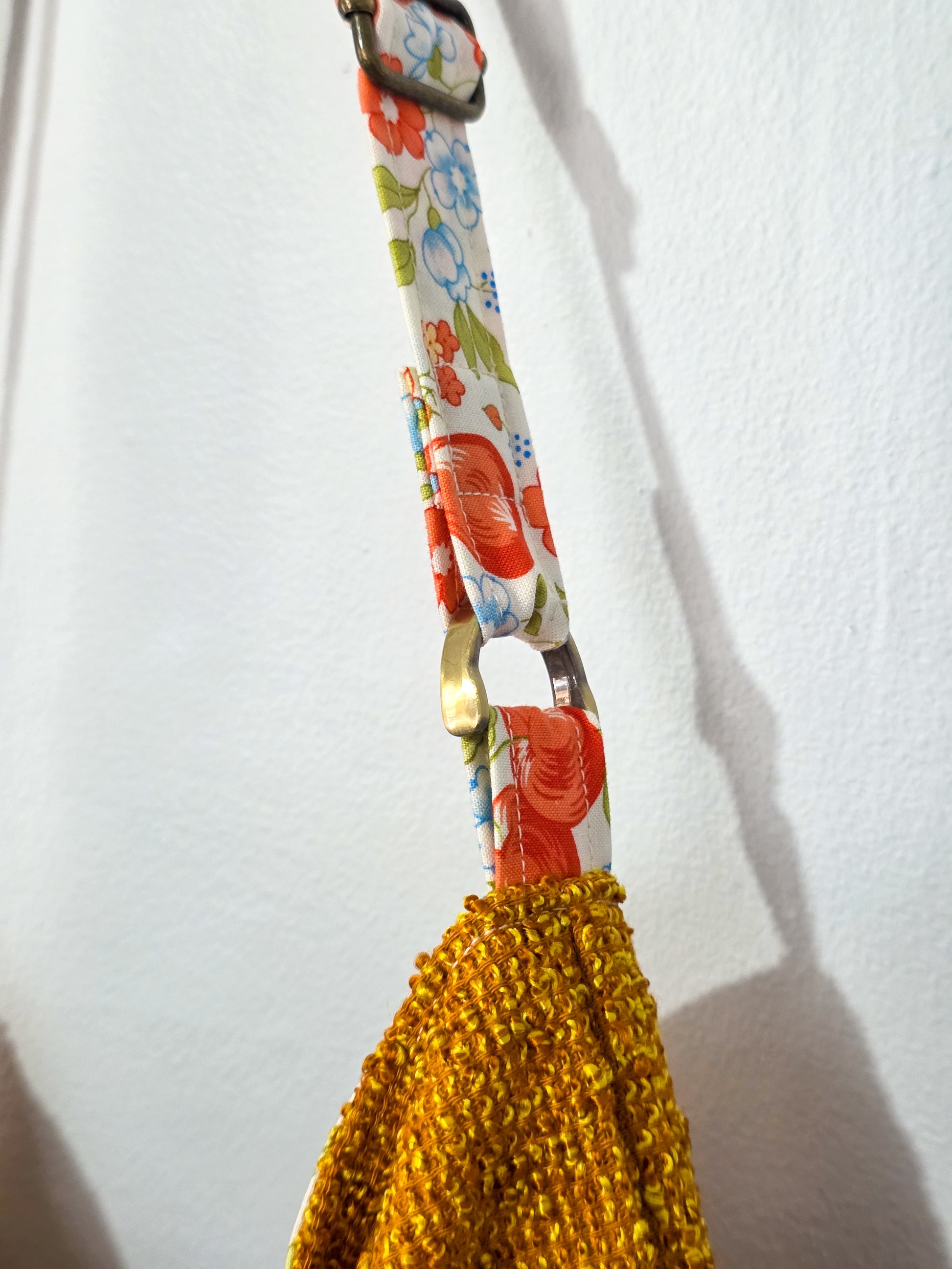 Bag strap with floral pattern and yellow textured end on a white background