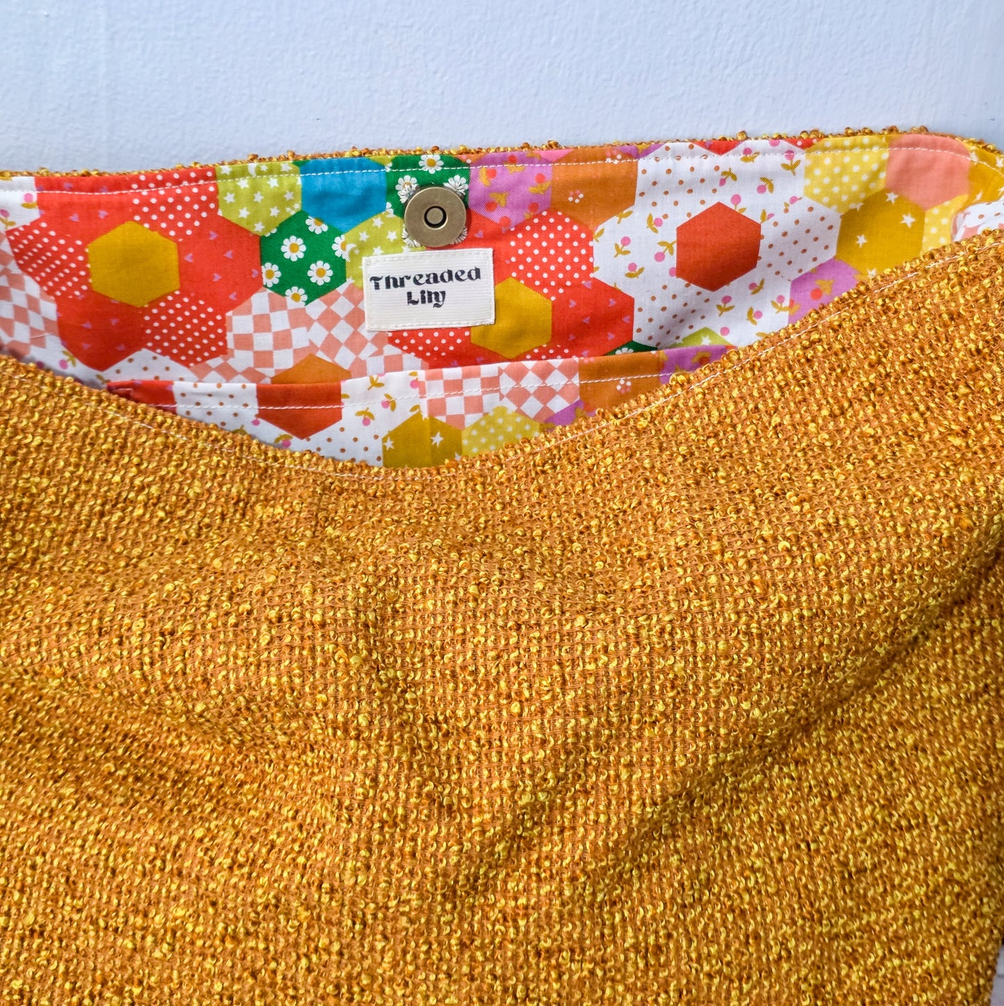 Close-up of a textured fabric with a colorful patchwork lining and a visible brand label.