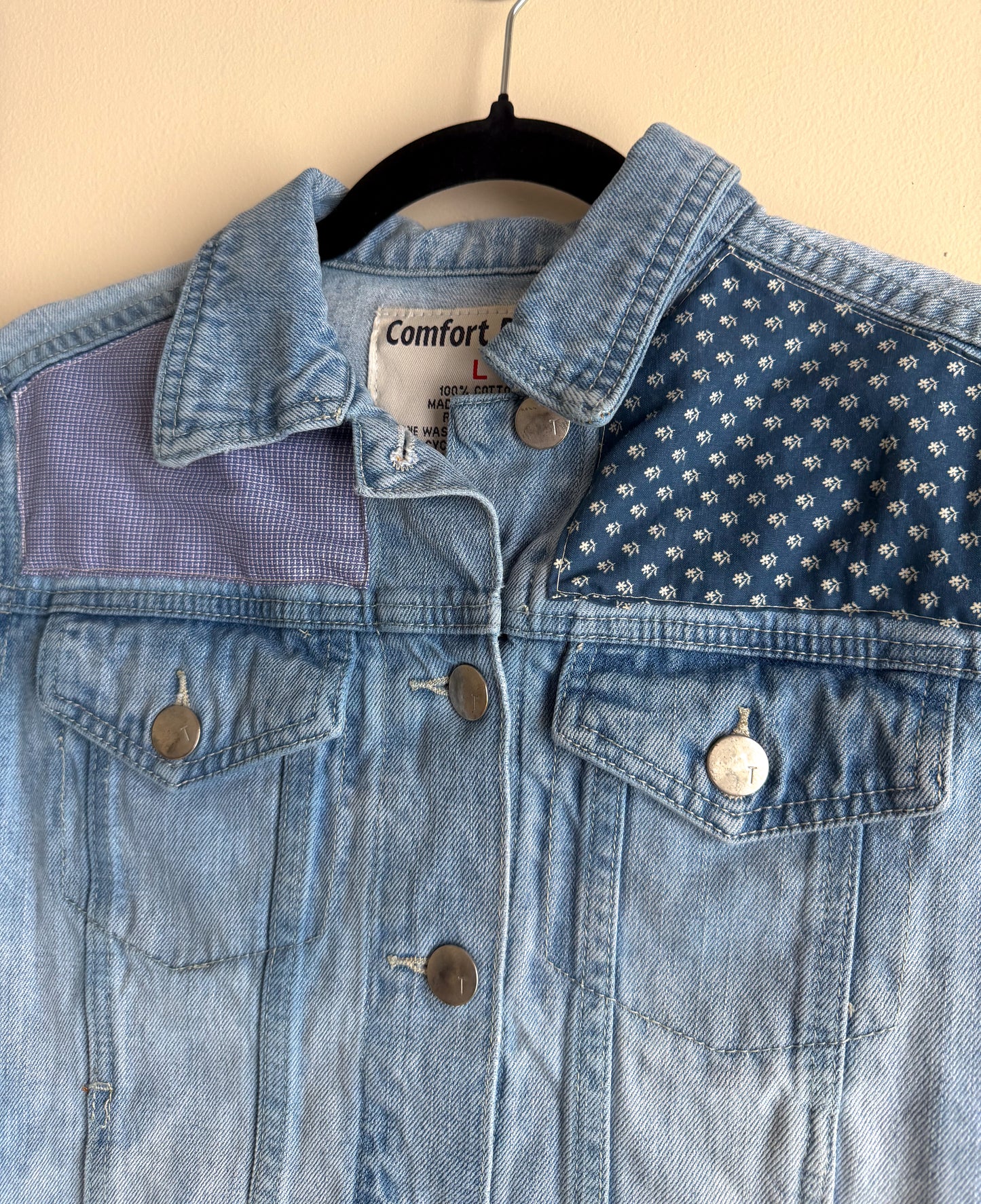 Blue denim jacket with a patterned shoulder on a beige background