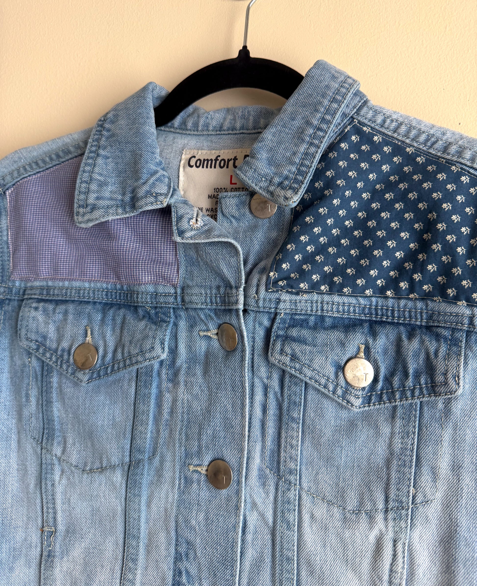 Blue denim jacket with a patterned shoulder on a beige background