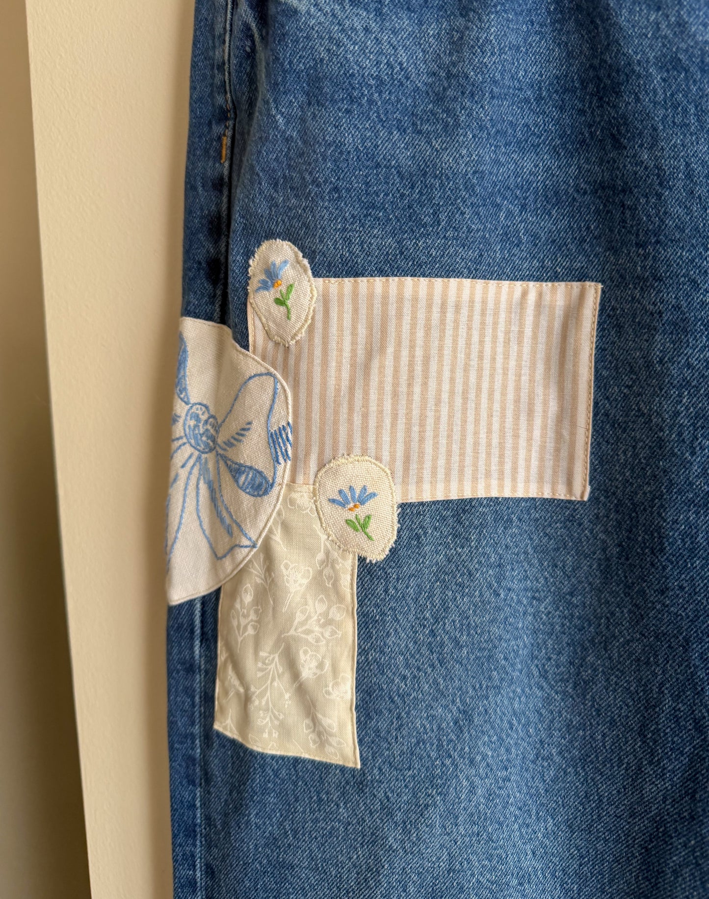 Blue denim jeans with embroidered details on a beige background