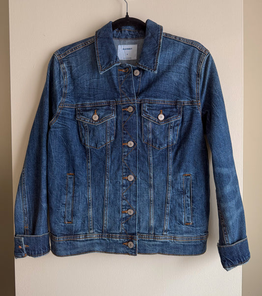 Blue denim jacket on a hanger against a beige wall