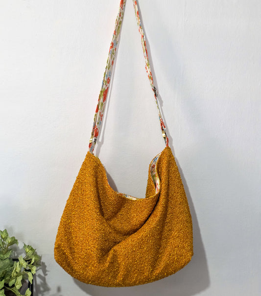 Yellow textured handbag with a floral-patterned strap on a white background